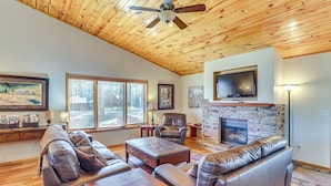 A spacious living room with leather sofas, a fireplace, a flat-screen TV, and a ceiling fan. - Lead Home in the Mountains w/ Hot Tub + Views! (Lead)