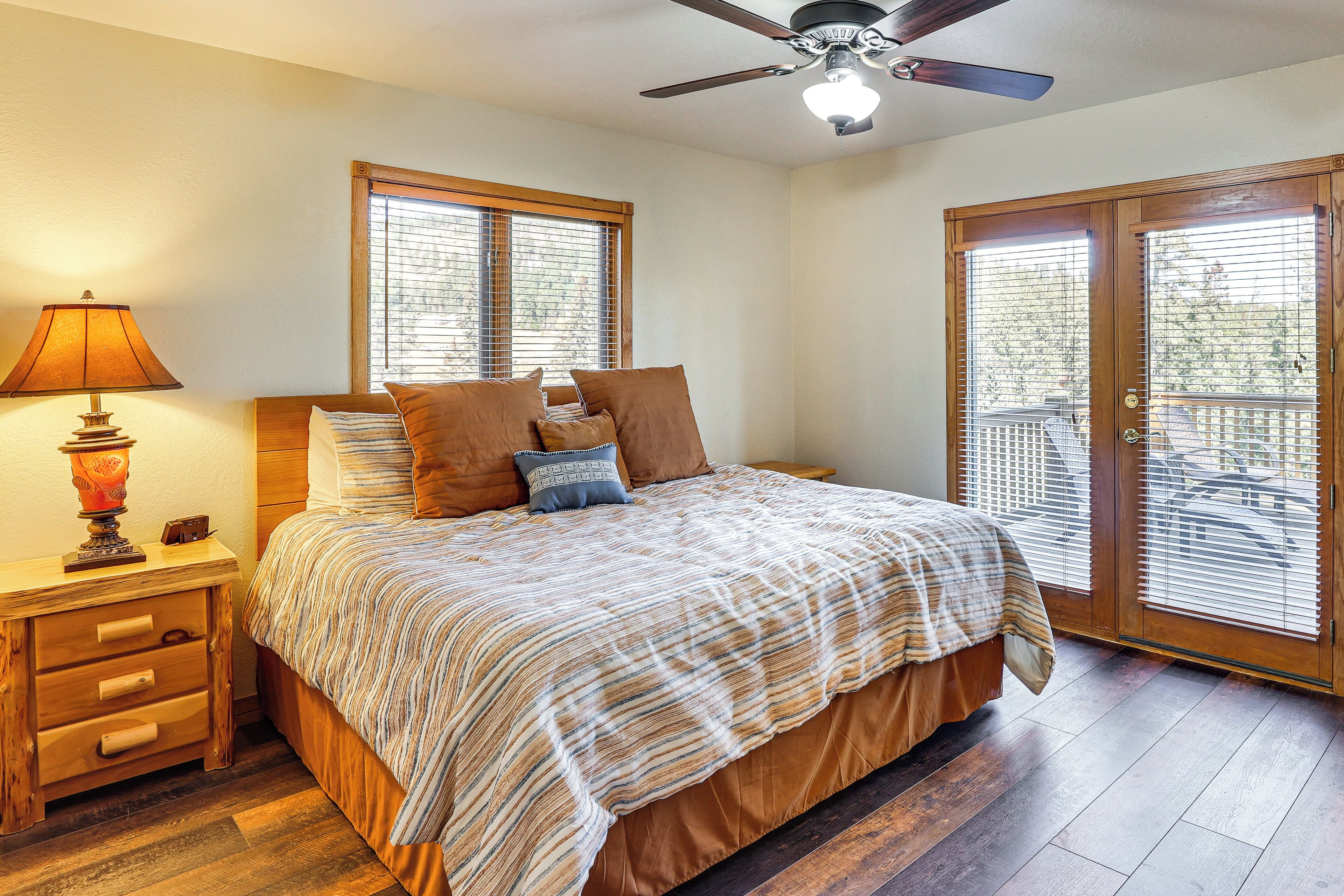 A bedroom with a bed, a nightstand, a lamp, a ceiling fan, and a sliding glass door leading to an outdoor area.