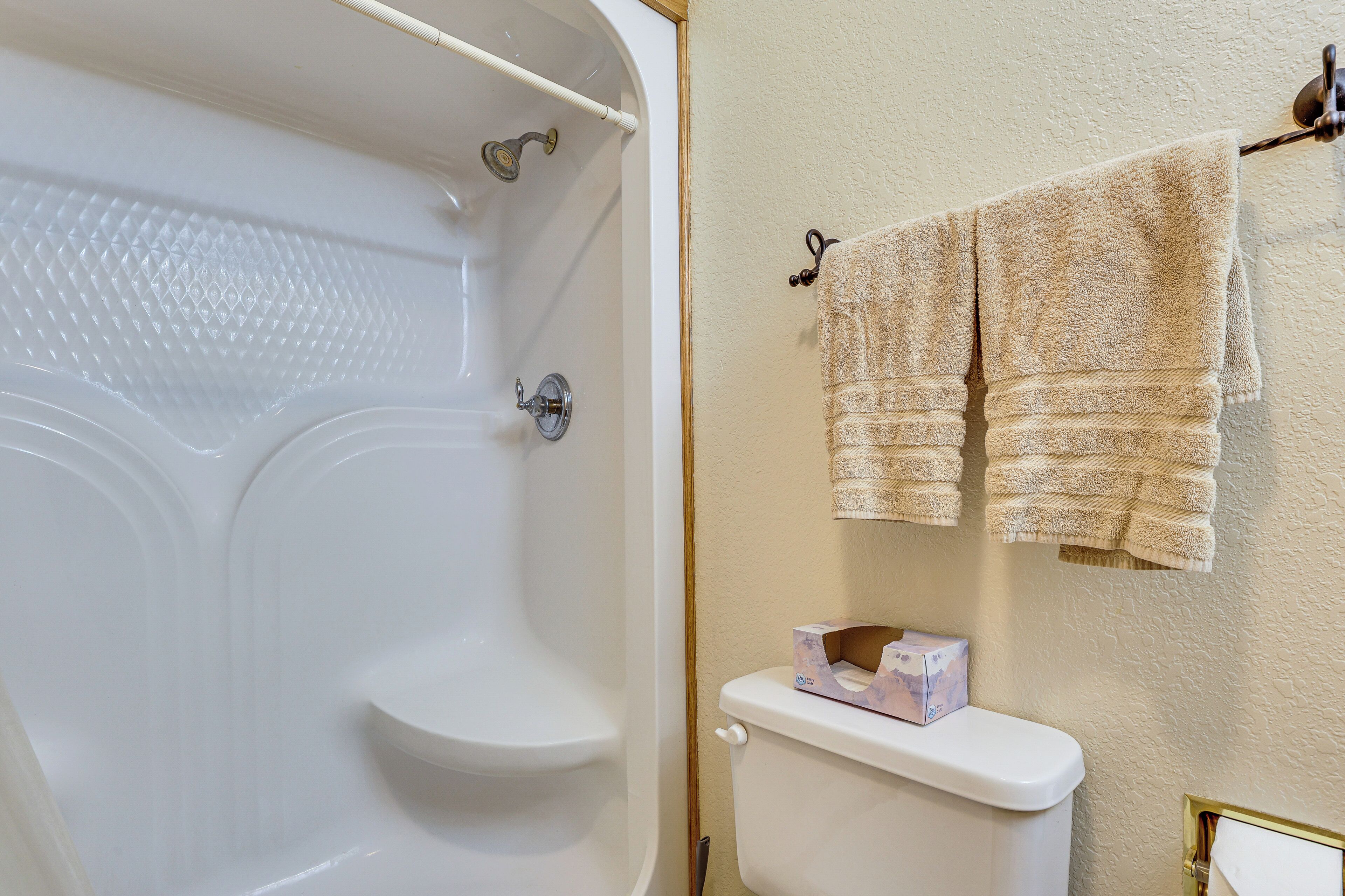 Un baño con bañera, inodoro y un perchero con toallas.