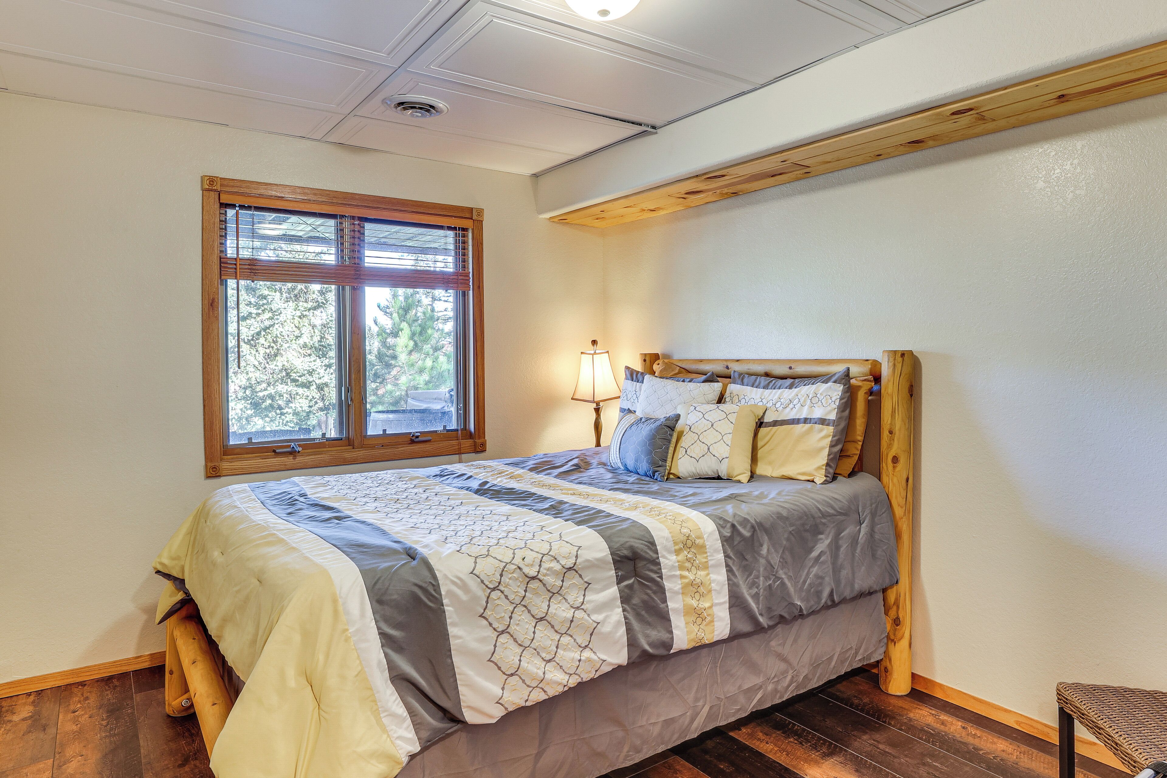 Une chambre à coucher avec un grand lit, une fenêtre avec des stores, une tête de lit en bois et une lampe sur une table de chevet.