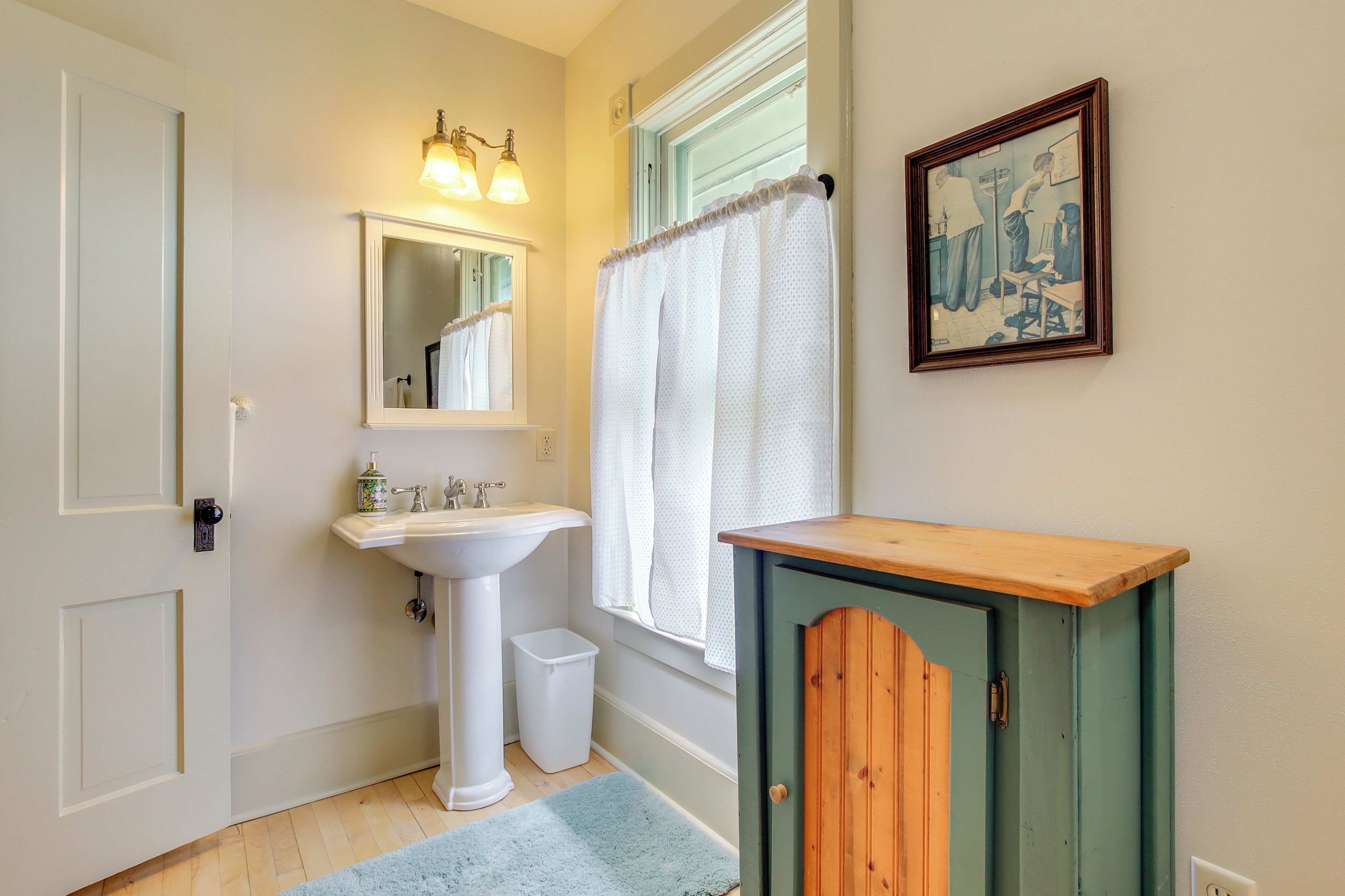A bathroom with a sink, mirror, and cabinet.