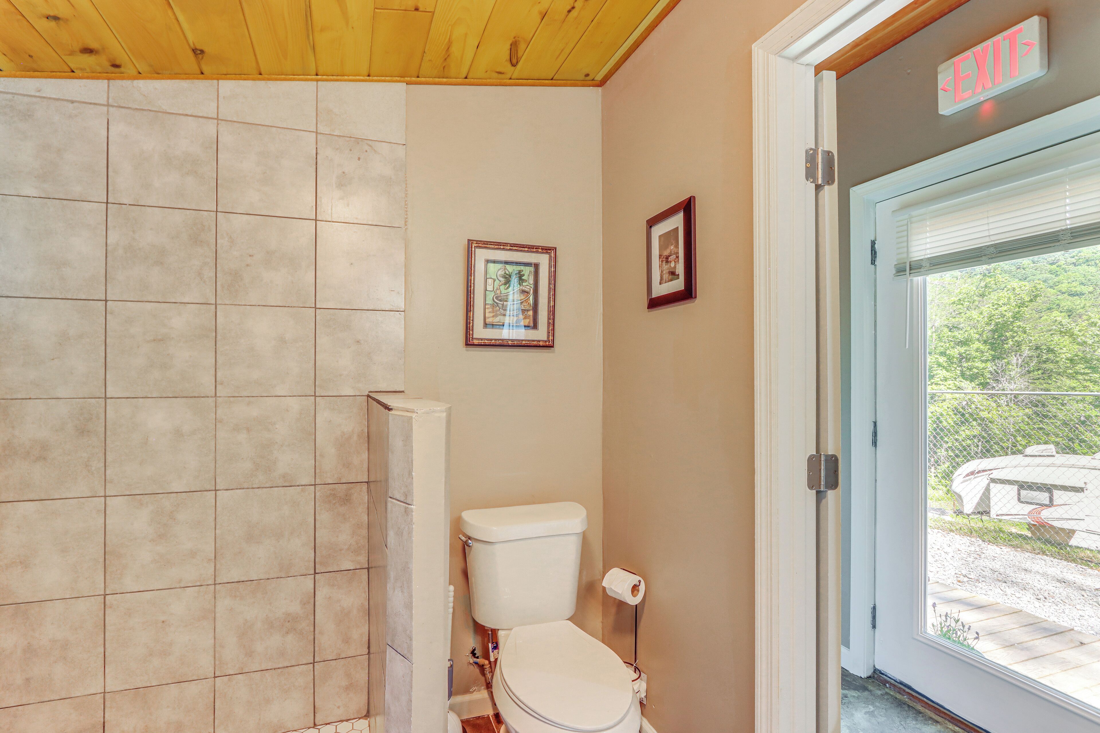 A bathroom with a toilet, a shower, and a door leading outside.
