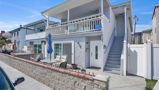 Une maison à deux étages dotée d’un balcon, d’une terrasse couverte et d’un escalier menant à l’étage supérieur.