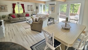 A spacious living area with a wooden dining table, white chairs, a sofa, and a coffee table. - Daybreak Limit 8 3 Bedroom Villa by RedAwning (Sebago)