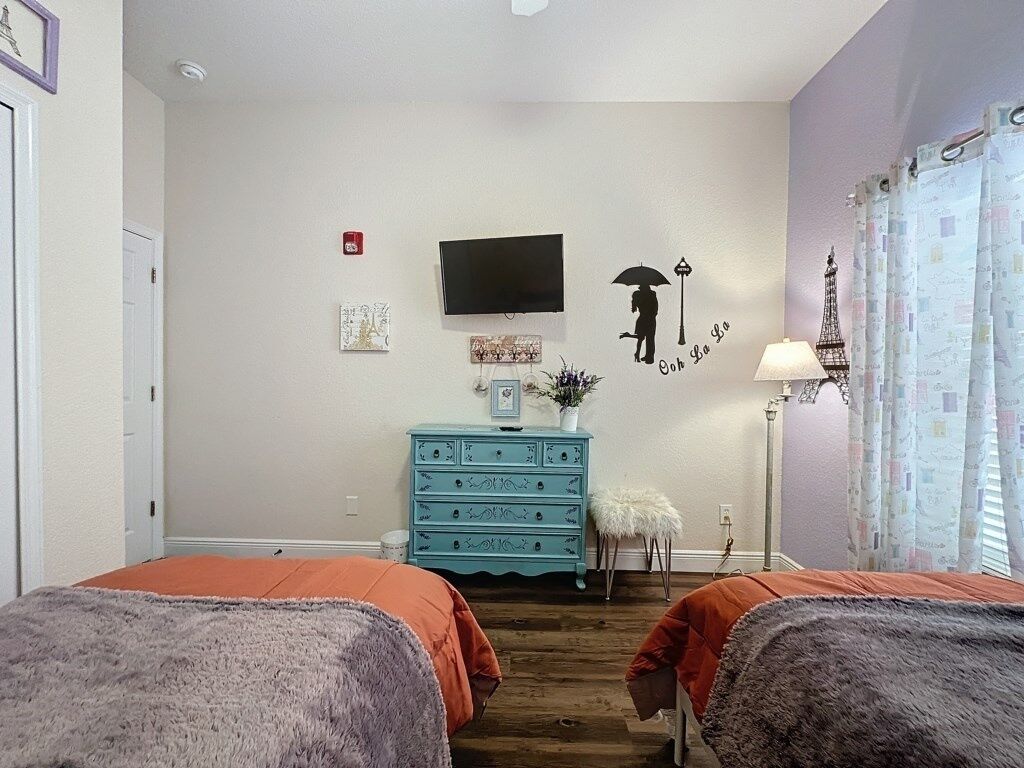 Een slaapkamer met twee bedden, een dressoir, een televisie en decoratieve wandkunst.