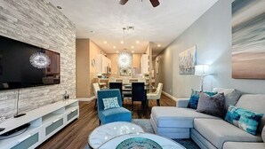 A modern living room with a flat-screen TV, a ceiling fan, and a dining area with a chandelier. - 3 Bed 2 Bath Condo Bahama Bay Resort 3 Bedroom Condo by RedAwning (Davenport)