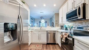 A modern kitchen with stainless steel appliances, white cabinetry, and a wooden floor. - 3 Bed 2 Bath Condo Bahama Bay Resort 3 Bedroom Condo by RedAwning (Davenport)