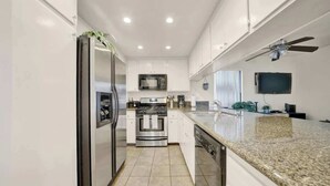 Una cocina moderna con armarios blancos, electrodomésticos de acero inoxidable y encimera de granito.