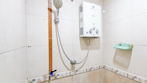 Baño con ducha, calentador de agua y un estante pequeño.