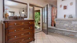 A wooden dresser with drawers, a mirror, and a lamp in a room with a stone wall and a window with curtains. - Typical Istrian stone house,6 persons,beautiful panoramic view of the sea,garden (Kastelir)