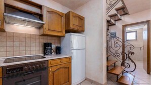 A kitchen with wooden cabinets, a stove, a refrigerator, and a coffee maker. - Typical Istrian stone house,6 persons,beautiful panoramic view of the sea,garden (Kastelir)