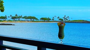A tropical beach view with a drink on a railing. - Ocean Views Serene Vacation Escape Home Near Beach w/Beach Equipment & Games (Waianae)