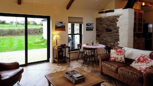 A cozy living room with a brown leather sofa, a wooden coffee table, and a stone fireplace.