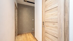 Un pasillo con piso de madera, pared texturizada y puerta de madera.