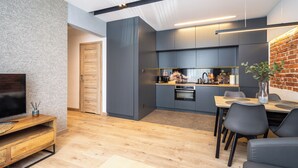 Una cocina moderna con armarios grises, una mesa de comedor de madera y una pared de ladrillo decorativa.