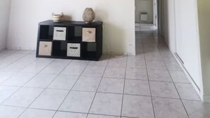 Una habitación con techo de madera, una consola negra con adornos y suelo de baldosas.