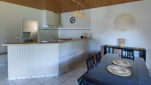 Una cocina moderna con techo de madera, una isla central y un comedor con mesa y sillas.