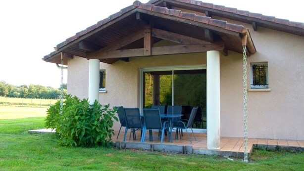 Un patio cubierto con mesa y sillas, una pérgola y vistas del paisaje circundante.