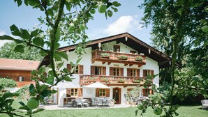 Un edificio a due piani con un balcone, posti a sedere all'aperto e un giardino.