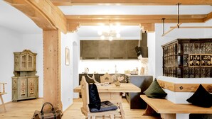 Un interno rustico con travi in legno, un'area pranzo con una panca e un mobile contenente oggetti decorativi.