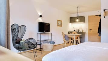 A hotel room with a bed, a TV, a desk with a chair, and a wooden door.