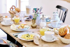A breakfast table with plates of scrambled eggs, toast, and fruit, along with cups of coffee and orange juice. - Der Lederer Hof (Tegernsee)