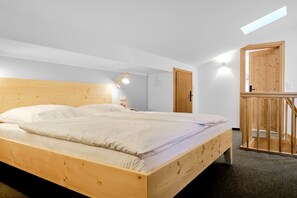 A bedroom with a wooden bed, a small desk, and a wooden wardrobe. - Der Lederer Hof (Tegernsee)