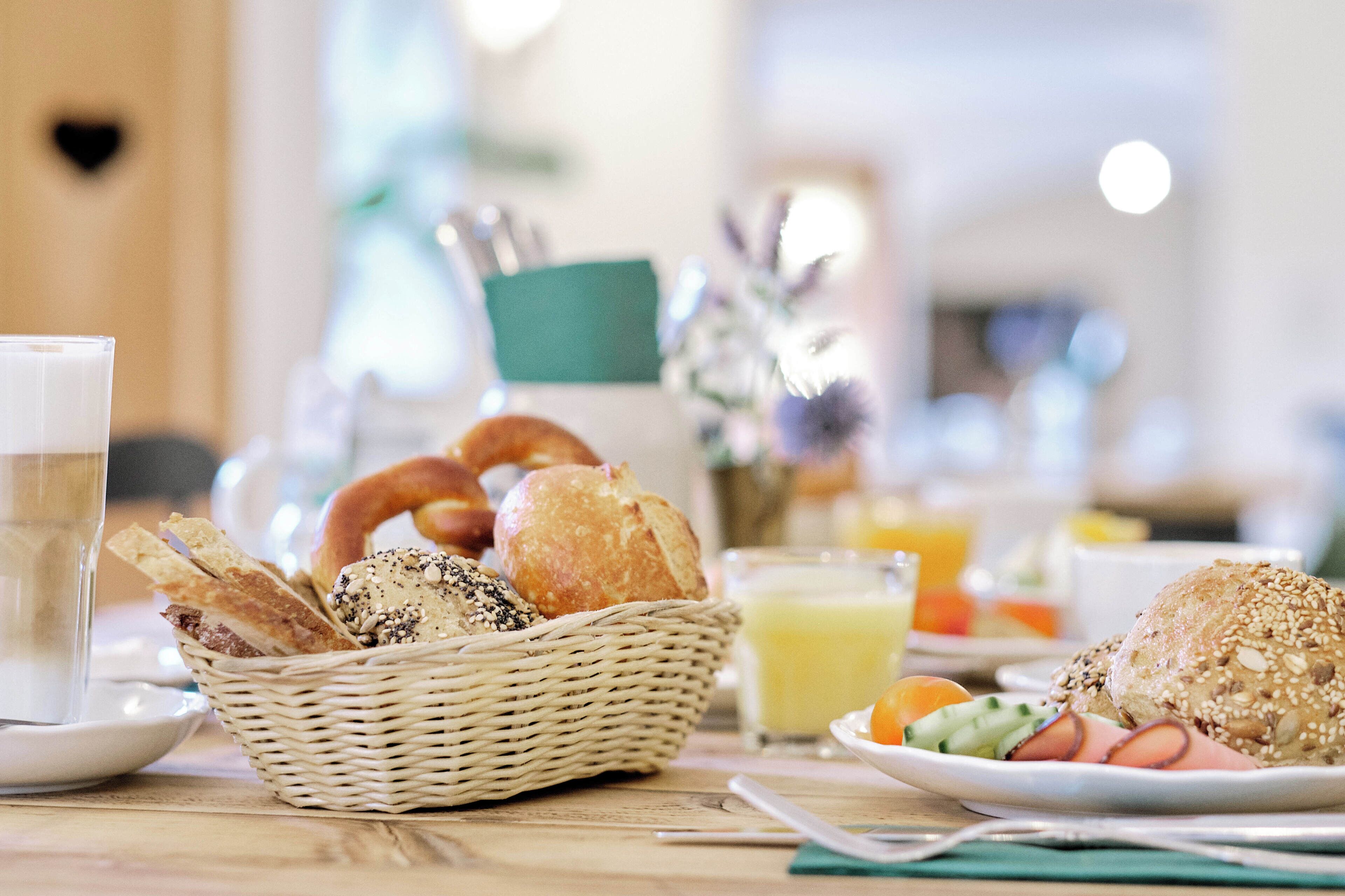 A breakfast setting with bread, a glass of juice, and a plate with vegetables.