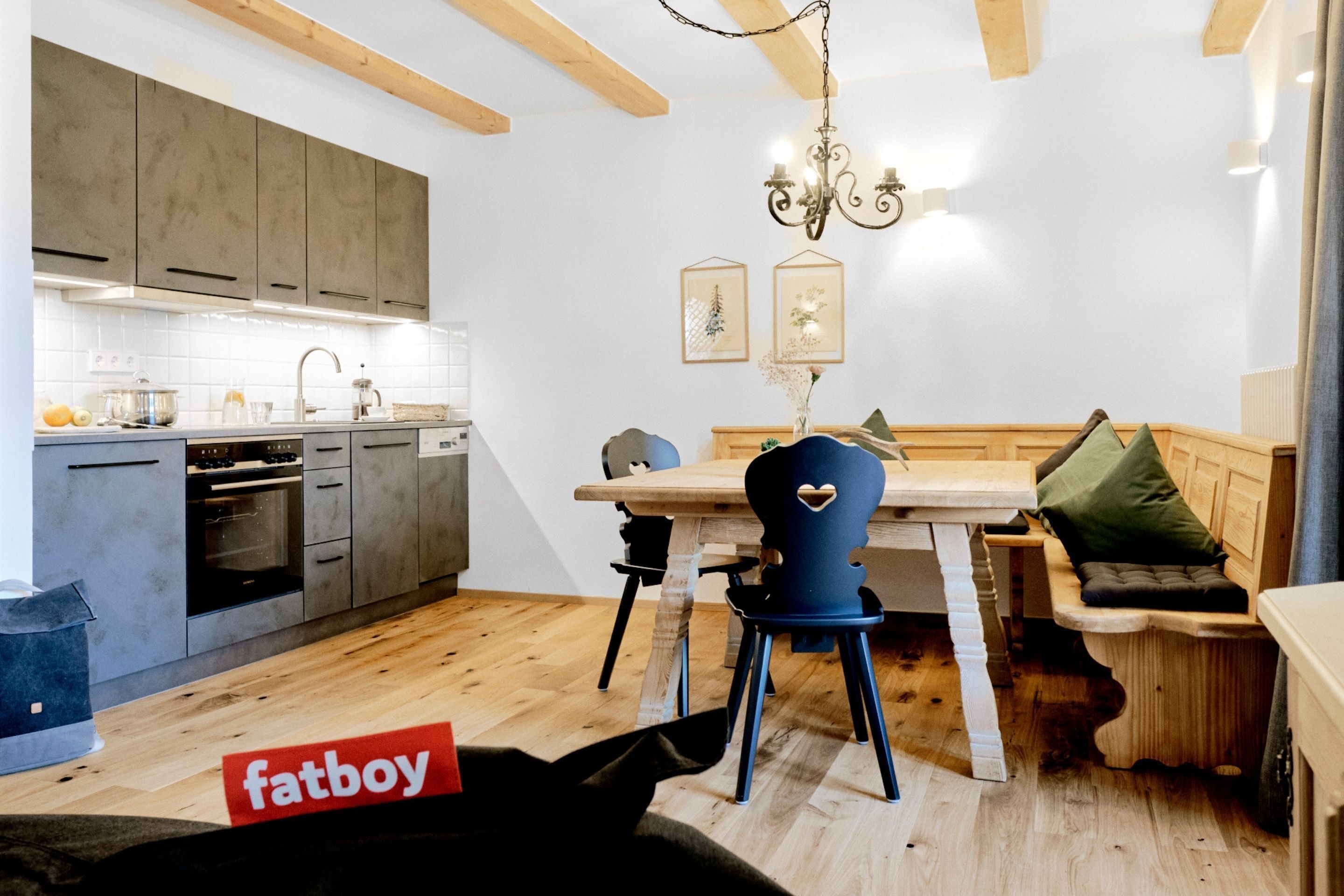 Een moderne keuken met houten kasten, een eettafel en een inbouwbank.