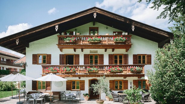 Tipico chalet con un balcone decorato da fiori, arredi da esterno e un giardino curato.