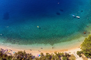 An aerial view of a beach with clear turquoise waters, a sandy shore, and a few boats. - Luxurious 7-Bedroom Villa MI with Heated Private Pool, Billiard Room, 500m from the Beach (Jesenice, Dugi Rat)