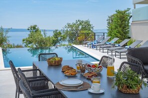 A dining table with breakfast items and a view of a pool and sea. - Villa Apolina 4-en-suite bedrooms, heated 36sqm pool, sea views, beach 1km (Podstrana)