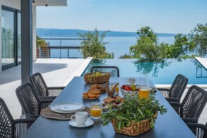 A dining table with breakfast items, a view of a lake, and a pool. - Villa Apolina 4-en-suite bedrooms, heated 36sqm pool, sea views, beach 1km (Podstrana)
