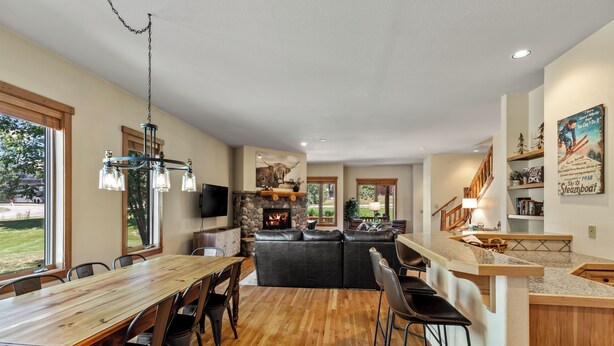 A spacious living area with a wooden dining table, black leather sofas, and a stone fireplace. - Relax and Recharge at The Retreat at The Enclave – Mountain Views, Hot Tub, and (Steamboat Springs)