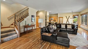 A spacious living area with a wooden staircase, a leather sofa, and a dining area. - Relax and Recharge at The Retreat at The Enclave – Mountain Views, Hot Tub, and (Steamboat Springs)