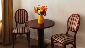 Un coin repas avec une table ronde, deux chaises et un vase de fleurs.