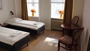 Une chambre d’hôtel avec deux lits, une table à manger et des chaises.