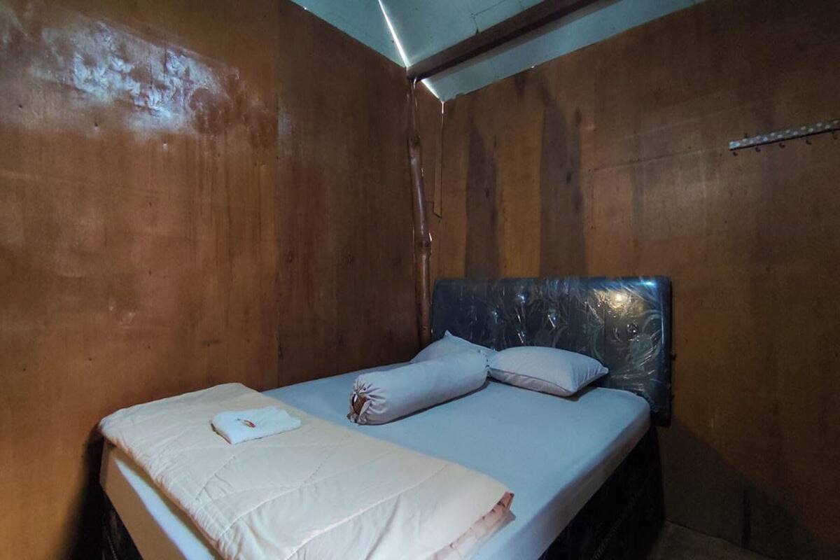 Ein Einzelbett mit Holz-Kopfteil in einem Raum mit Holzwänden.