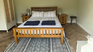Un dormitorio ordenado con una cama de madera, dos mesitas de noche, un armario y una alfombra estampada.