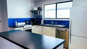 Una cocina moderna con encimera negra, armarios blancos, microondas integrado, estufa, fregadero y lavavajillas.