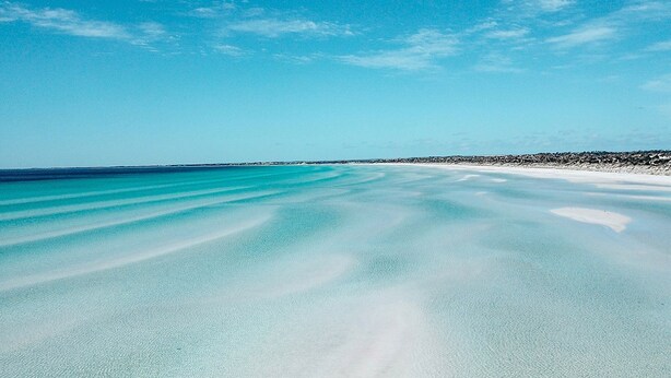 Una vista despejada de una playa con una orilla arenosa y un mar tranquilo.