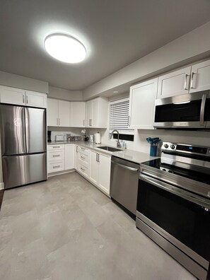 A modern kitchen with stainless steel appliances, white cabinetry, and a central island.