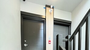 A staircase with a wooden finish, a black door, and a red emergency button. - Your Home Away From Home in Ottawa - close to work, schools, hospitals, parks (Ottawa)