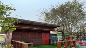 Une cabane en bois avec une porte rouge, un petit porche et une pelouse artificielle verte.