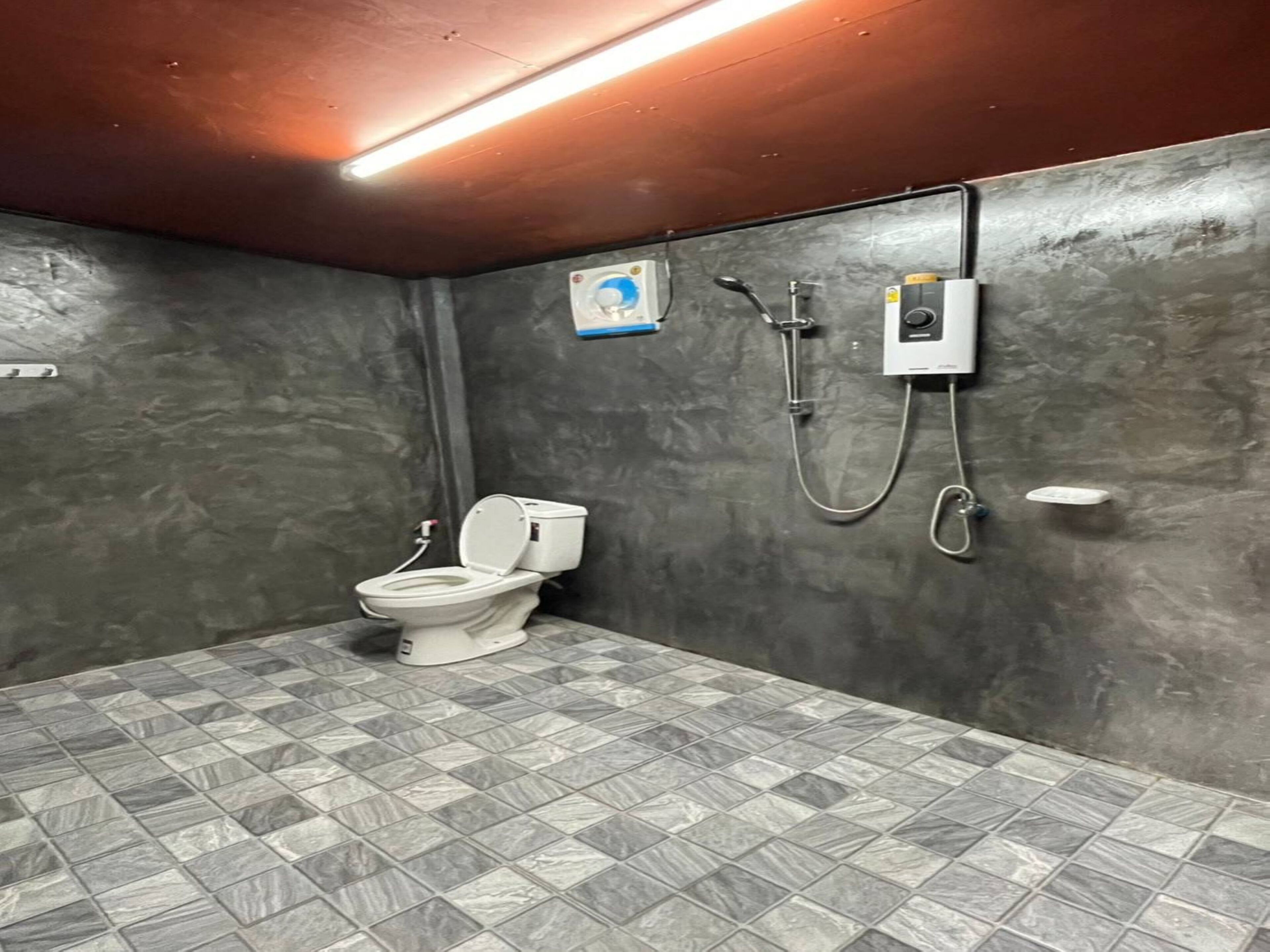 Un baño con inodoro, ducha y piso de baldosas.