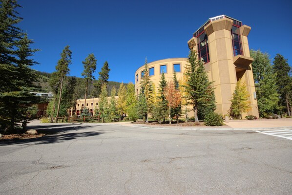 A multi-story building with a central tower, surrounded by trees and a clear sky. - Spacious 2 story condo, Hot tub on site! (Keystone)