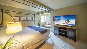 Une chambre à coucher avec un lit, une télévision, une lampe et des tableaux encadrés accrochés au mur.