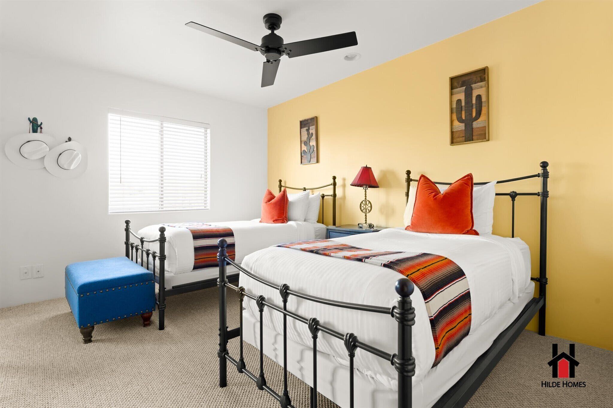A bedroom with a bed, a bench, a ceiling fan, and a window.