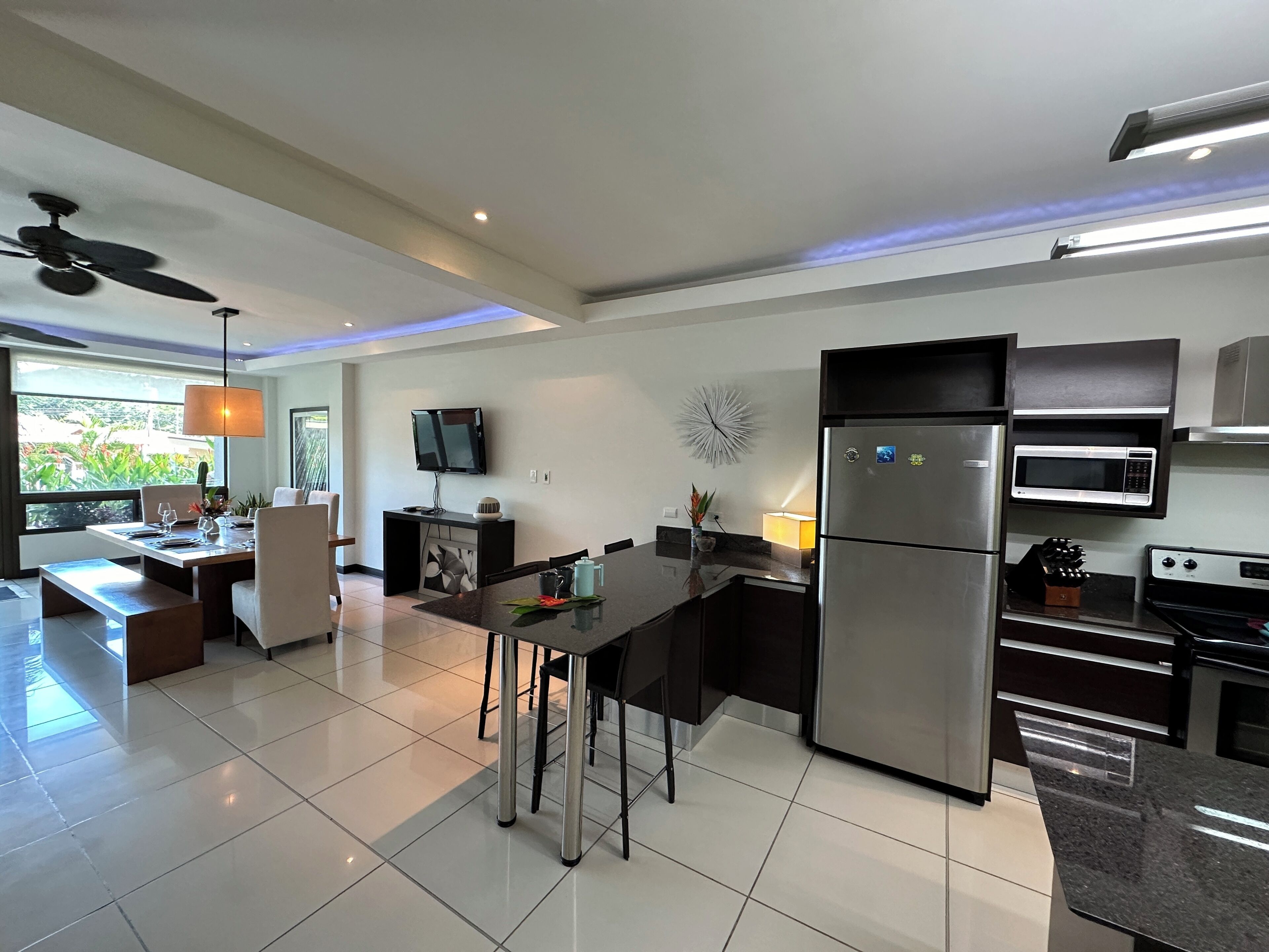 A modern kitchen with a central island, built-in appliances, and a dining area with a view.