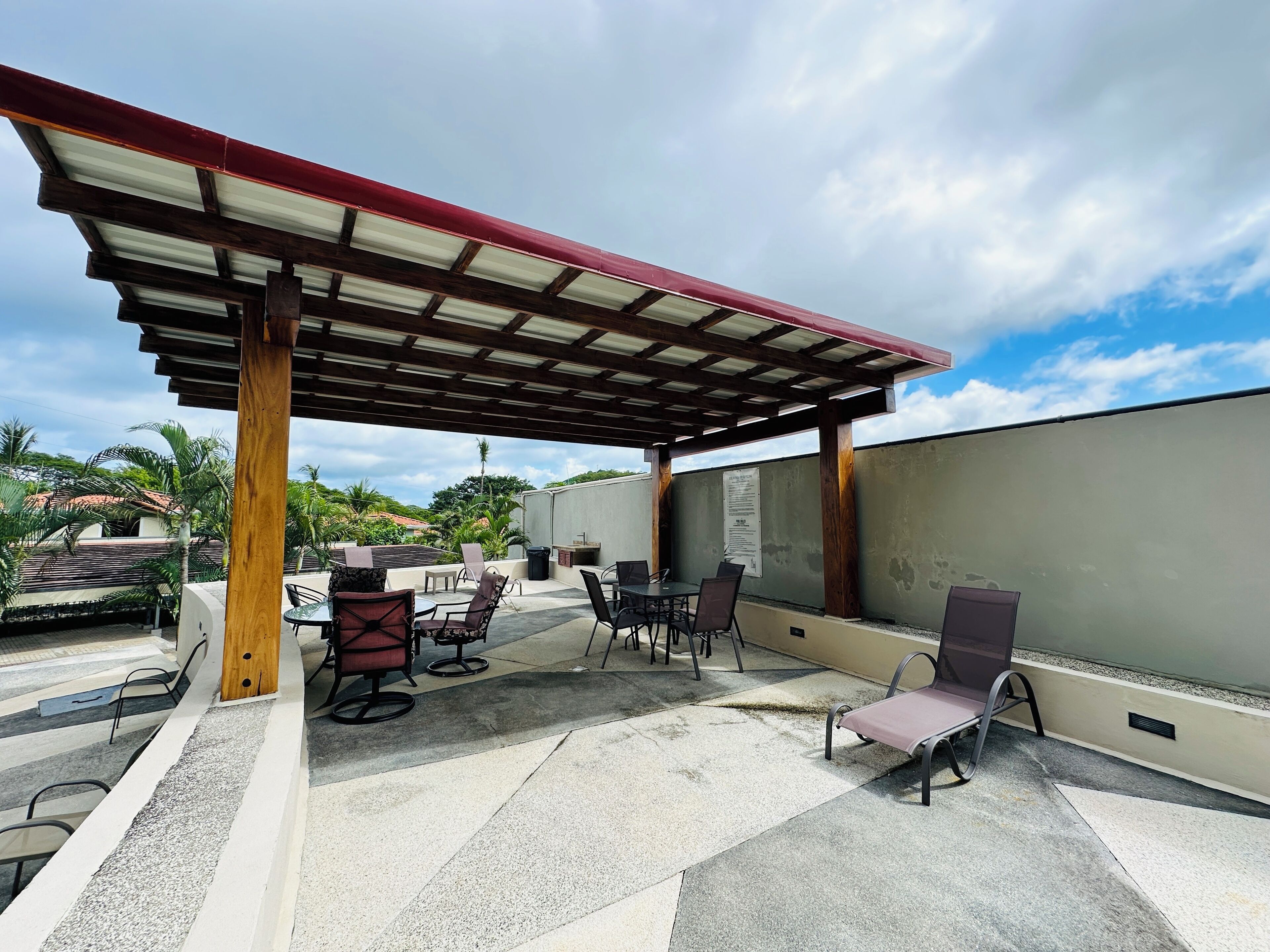 An outdoor patio with a covered seating area, tables, and chairs.